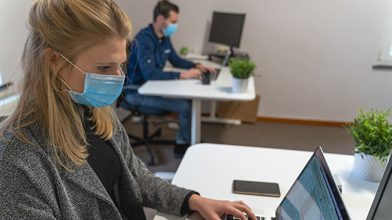 Woman wearing mask at a computer